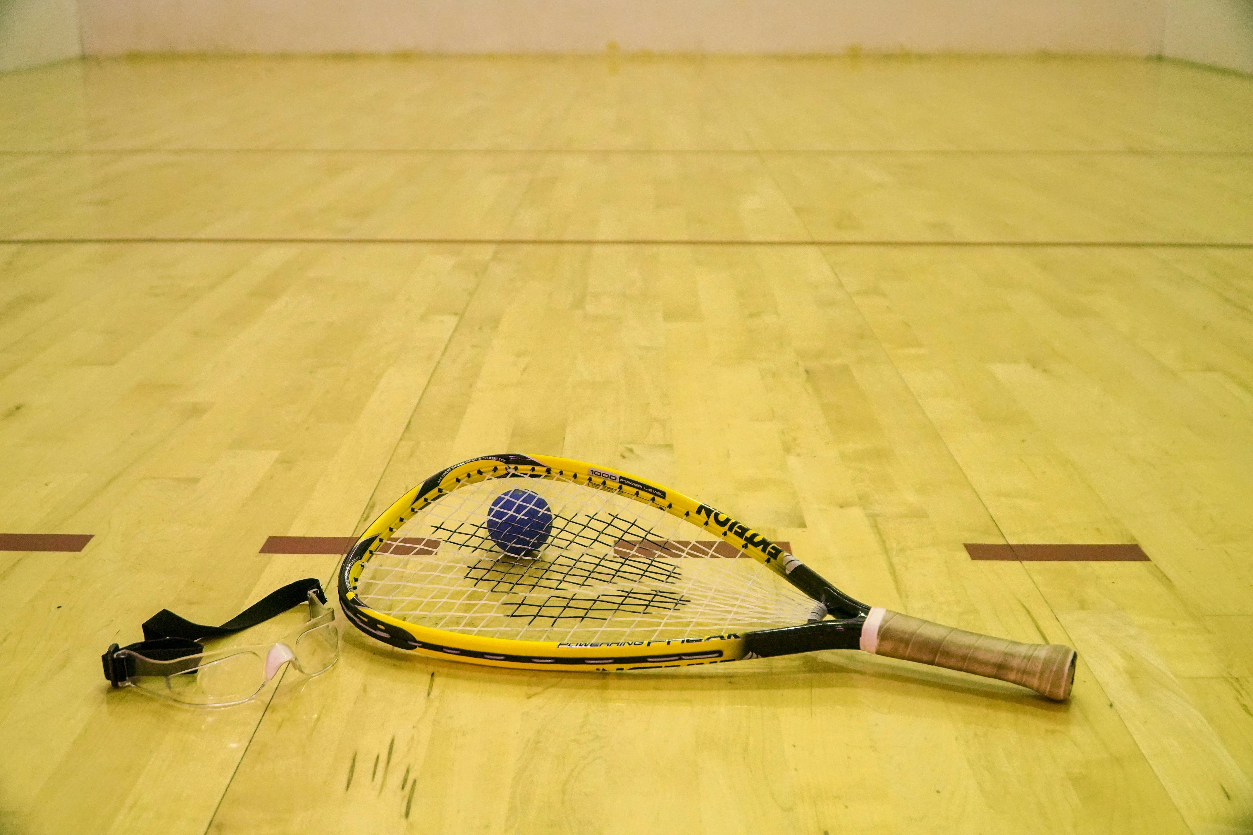 black ball beside yellow and black racquetball racket