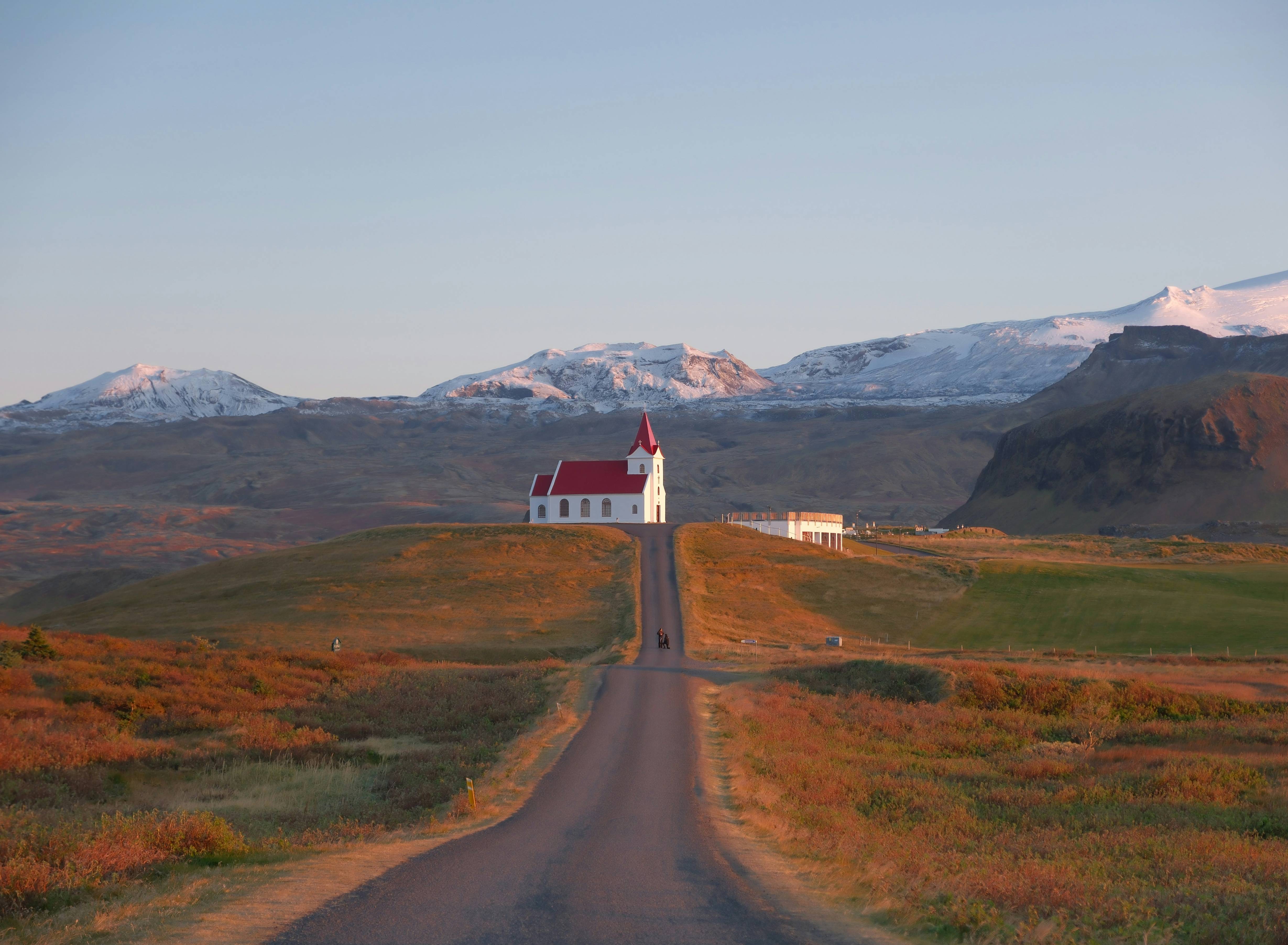 Church and road amidst rolling hills and mountains.