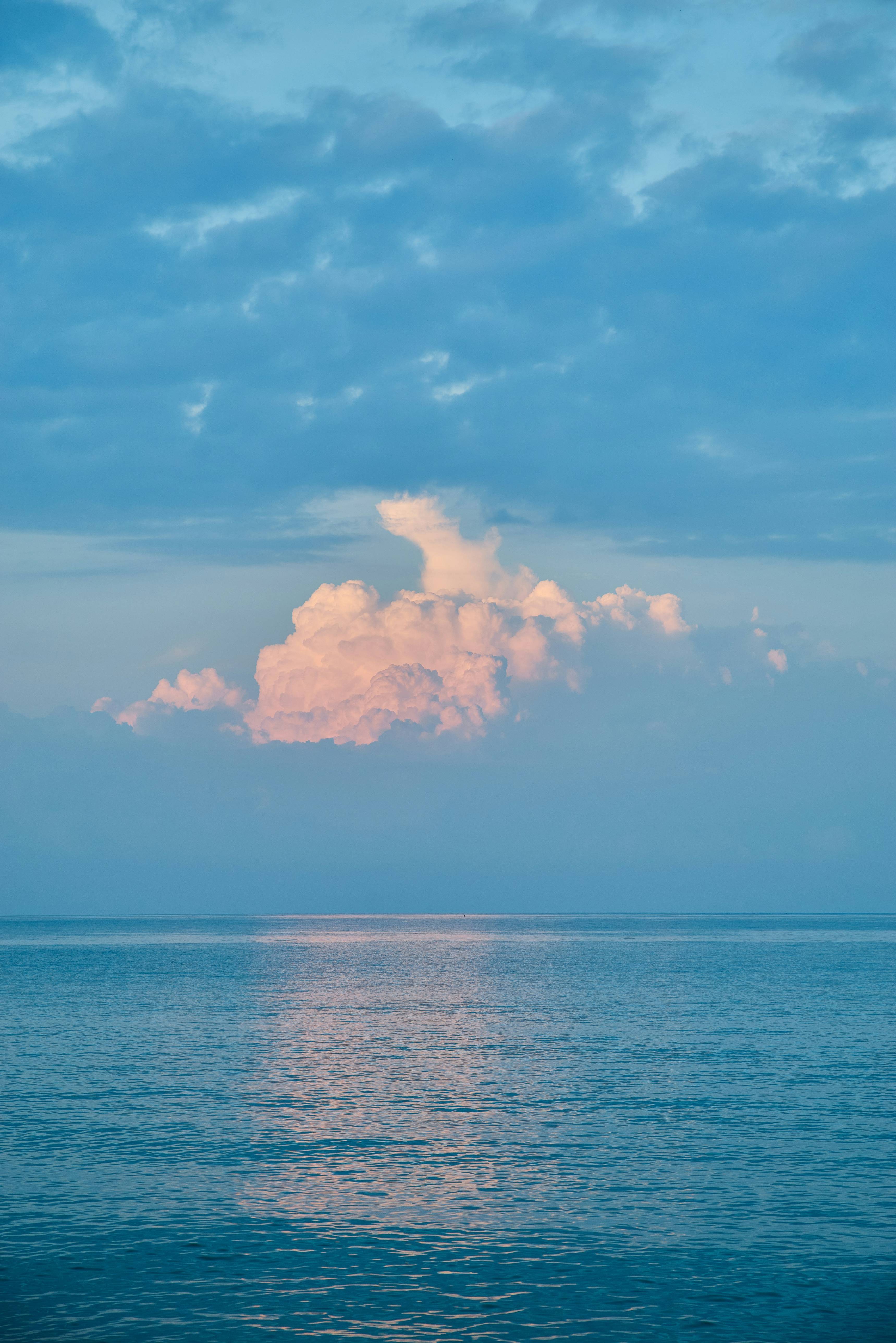 a large cloud is floating in the sky over the ocean